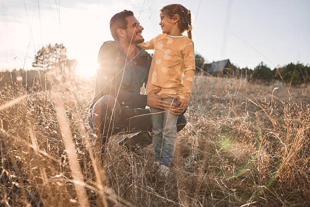 A waist-up close up of a father and daughter son spending the day at the beach in Seahouses in the North East of England He is carrying his son in his shoulders as they wander through the sand dunes.
