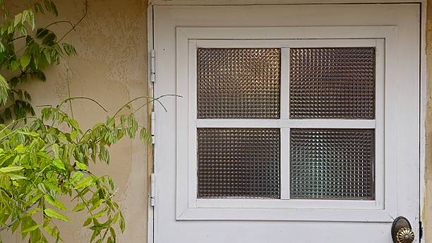 istock White Textured Glass Door with Brass Handle and Surrounding Greenery 2214643953
