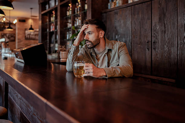 istock Depressed Young Adult Drinking Alone at Bar 2214644375