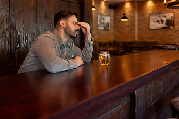 istock Man Drinking Alcohol Alone in Bar, Showing Signs of Depression 2214644525