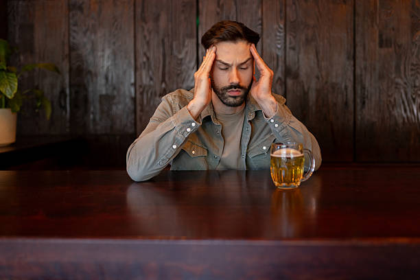 istock Man Drinking Alcohol Alone in Bar, Showing Signs of Depression 2214644528