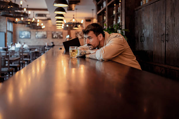 istock Depressed Young Adult Drinking Alone at Bar 2214644631