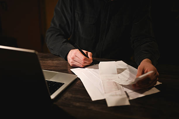istock Businessman working late at night doing paperwork and calculating bills 2214644853