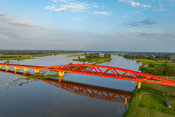 Hanzeboog train bridge over the river IJssel with a train passing over the red bridge near the city of Zwolle in Overijssel, The Netherlands. Aerial drone point of view.Amazing colorful sunset over the river IJssel in Overijssel, Netherlands during springtime seen from above.