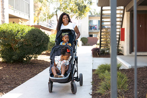 Single mother pushing a baby stroller with her two daughters.