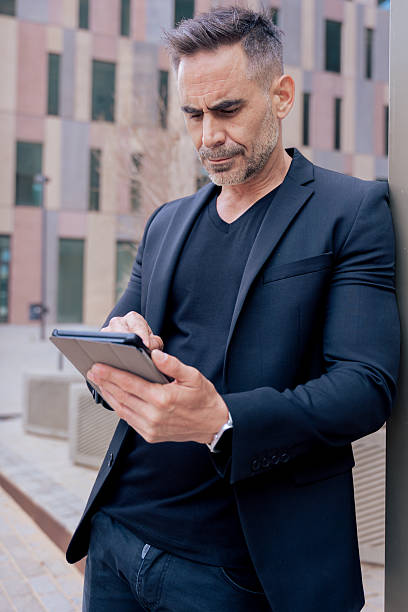 istock Businessman using tablet outdoors in modern city, focused on digital technology 2214650202