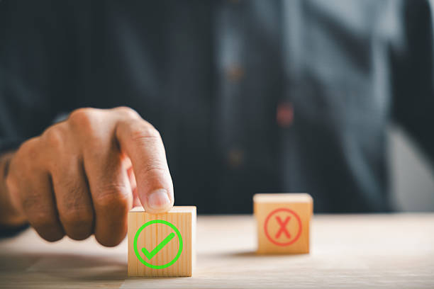 istock Businessman indicates between wooden cubes with check marks for right and wrong choices. Conveys choice validation in decision-making. Think With Yes Or No Choice. 2214650542