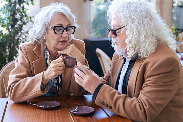istock Caucasian senior couple talking closely while drinking coffee at outdoor cafe 2214651901