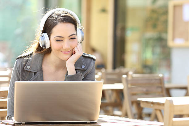 istock Woman with headphone in a bar terrace using laptop 2214653564