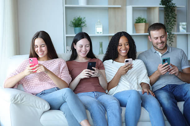 istock Four happy friends using everyone their phones 2214653588