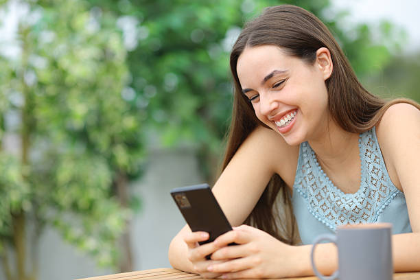istock Happy woman checking mobile phone sitting in a terrace 2214653635