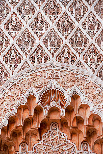 Traditional moroccan stucco work creating beautiful geometric patterns on a wall in Ben Youssef Madrasa, Marrakech, Morocco