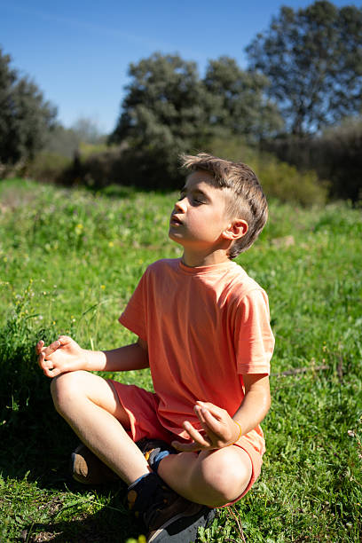 Elementary age boy practicing mindfulness in nature, promoting mental well-being and a connection with the environment