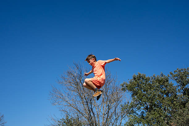 Boy having fun jumping high in the air against a clear blue sky