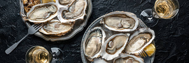 istock Fresh raw oysters on ice, overhead flat lay panorama of two platters 2214660793