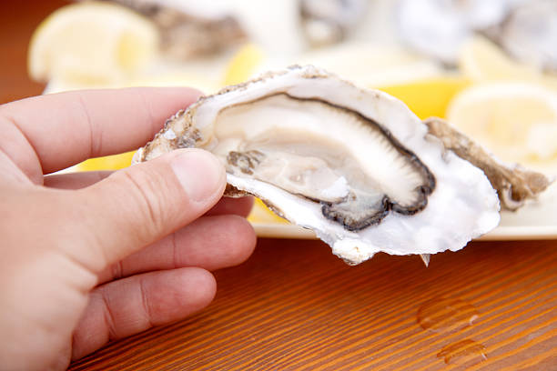 istock man's hand holding an oyster close-up 2214662944