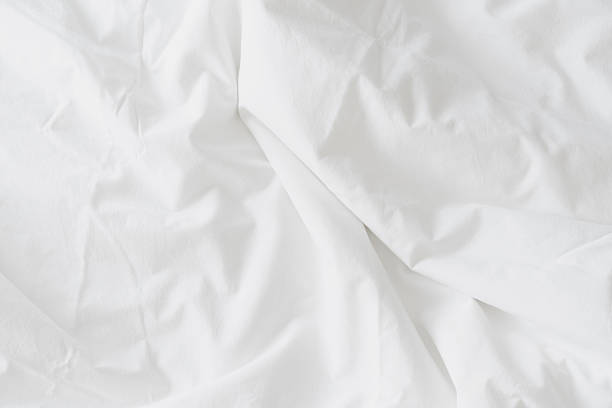 istock Abstract background of rippled white silk fabric, white fabric draped in soft waves empty bed sheet. Close up image. 2214663731