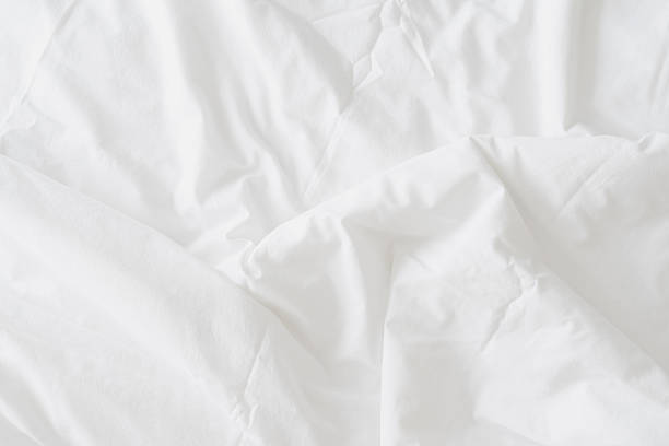 istock Abstract background of rippled white silk fabric, white fabric draped in soft waves empty bed sheet. Close up image. 2214663739