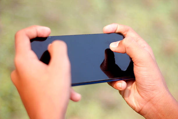 A Human hand holding a mobile phone and showing mobile screen and green background blur