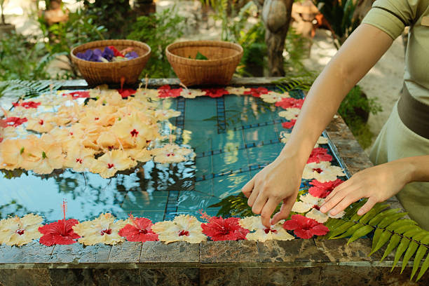 Masseuse carefully placing colorful hibiscus flowers on the surface of water to create a relaxing atmosphere in a Maldives spa