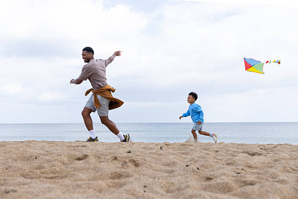 istock Father and Son Running with a Kite on the Beach 2214666799