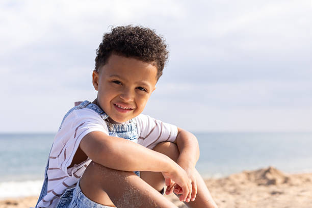 istock Smiling Young Boy Sitting on the Beach 2214666822
