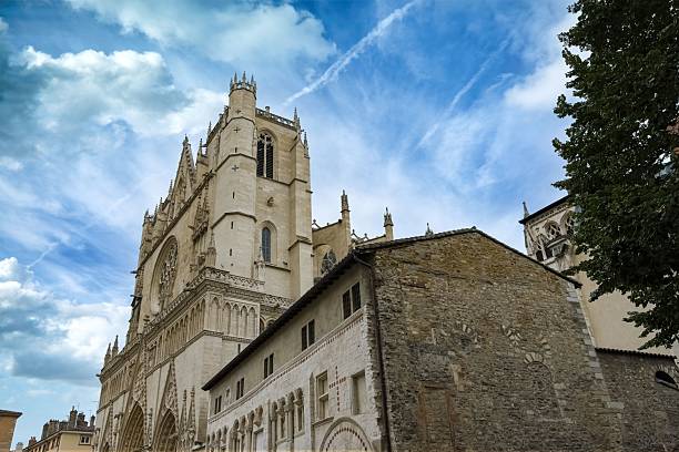 The Gothic architecture of the Saint-Jean-Baptiste cathedral in Vieux-Lyon rises against a partly cloudy sky.