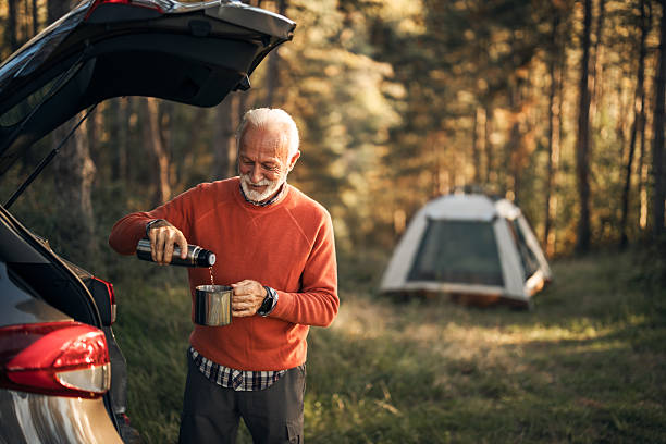 istock Senior Man Camping in Forest, Pouring Tea from a Thermos 2214669146
