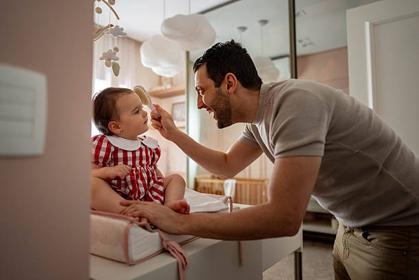istock Father brushing his daughter's hair at home 2214674394