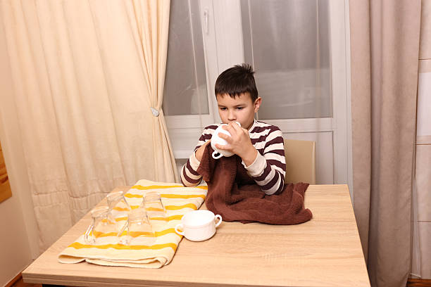 Boy wipes glasses and cups with a towel. Housework.