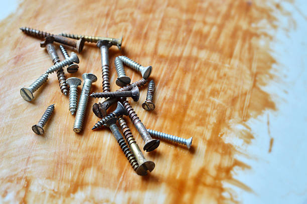 istock Heap or stack of several variety metal screws in different size scattered over rough slightly dusty acrylic blotched background with brown wood varnish or epoxy resin paint with messy brush strokes with copy space 2214678890
