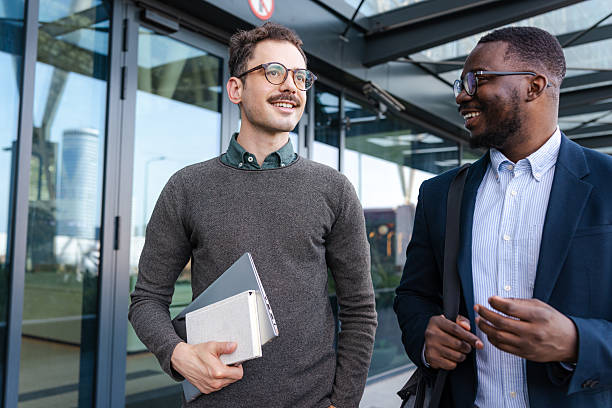 istock Two professionals smiling and conversing outside the office building 2214680446