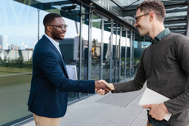 istock Two professionals shaking hands outside an office building 2214680489
