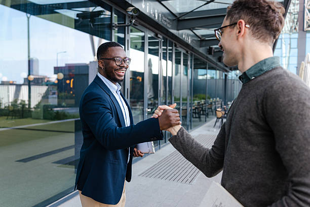 istock Two business professionals greet each other with a handshake outdoors 2214680502