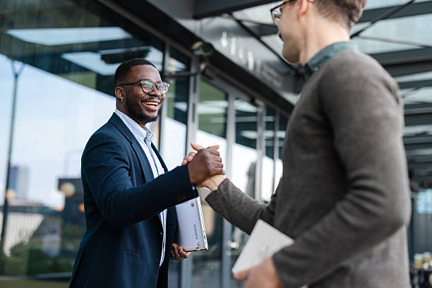 istock Two businessmen shaking hands outdoors in a positive and friendly business interaction 2214680556