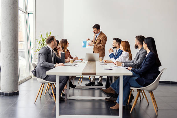 istock Team of experts sitting at boardroom with their leader who is explaining financial report. 2214683063