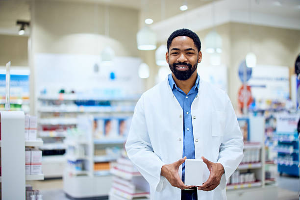 istock Friendly Pharmacist Holding Medication Box in a Well-Organized Pharmacy Store 2214683710