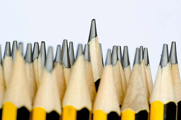 A yellow notebook with an elastic closure lies on a blue surface, accompanied by a white pencil. A circular daisy-like button rests on the notebook's cover. The setup exudes a sense of preparedness, suggesting the initiation of a task or project. A decorative paper band runs across the top.
