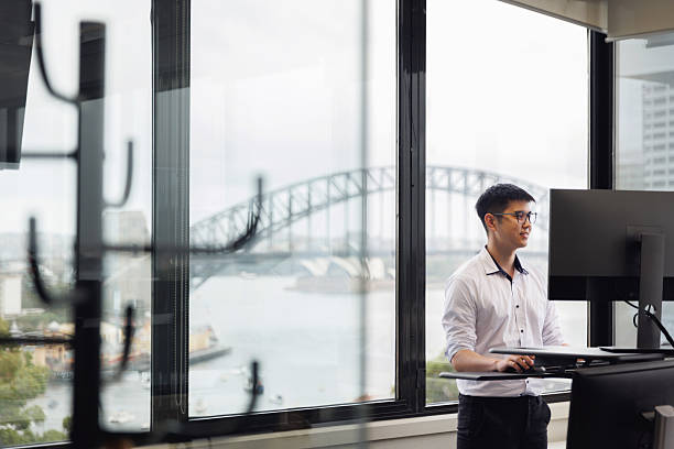 istock Employee working on a stand-up desk in corner office 2214689201
