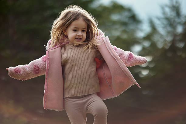 Cute happy girl having fun running in the forest during spring day