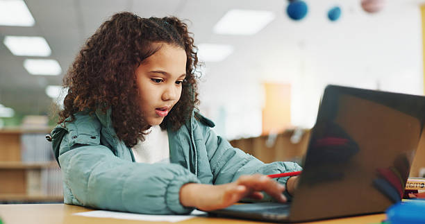 istock Student, girl and typing with laptop for exam, e learning or online class for knowledge. Virtual school, development and child on technology for project activity on teaching platform in library 2214689905