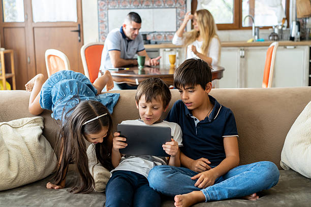 istock Three children using a digital tablet on the sofa at home 2214691841