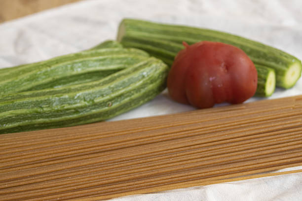 a rustic table featuring whole wheat spaghetti, fresh zucchinis, and a vibrant red tomato.  for healthy eating and Mediterranean cuisine concepts.