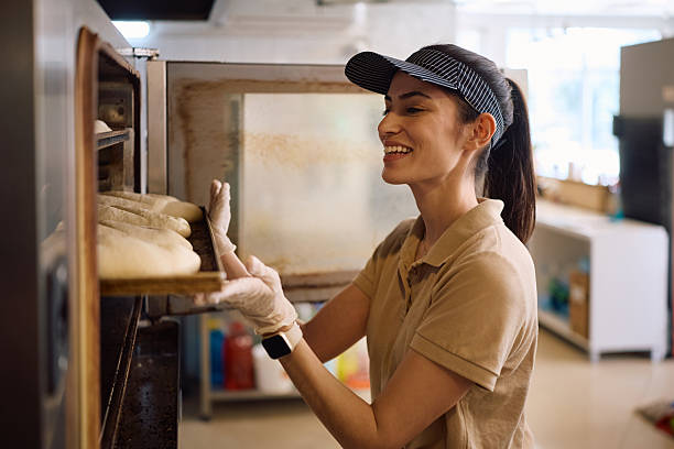 istock Happy female baker baking bread in the oven. 2214696584
