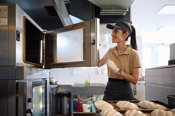 istock Happy female baker heating the oven for baking pastry. 2214696585