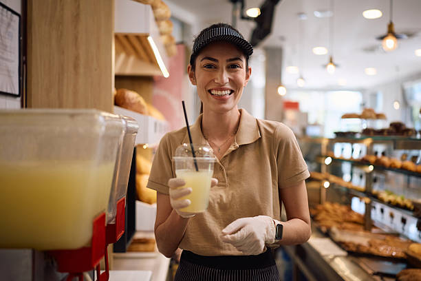 istock Happy female baker serving fresh lemonade and looking at camera. 2214696631