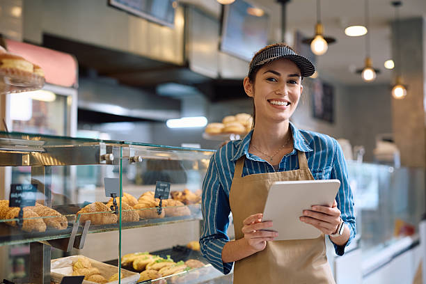 istock Young happy woman working on digital tablet in a bakery and looking at camera. 2214696840