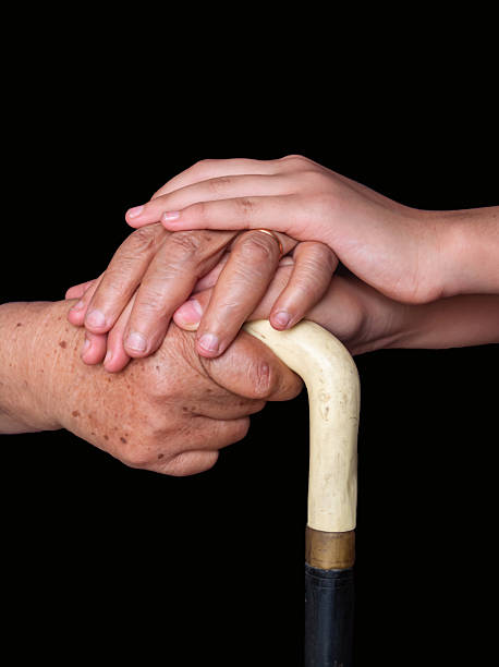 Touching moment of a young hand holding elderly hands on a cane. Symbol of love, support, family connection, and intergenerational care.