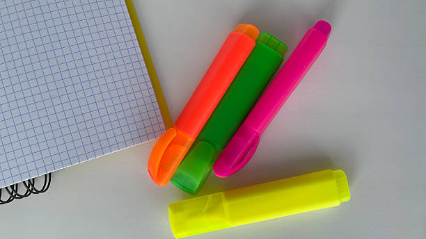 Brighten up your workspace with this colorful set of neon highlighters and a squared graph notebook, perfect for students, teachers, and office professionals. This eye-catching image is ideal for educational, organizational, or productivity-themed project