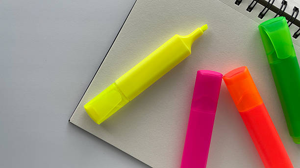 istock Bright neon highlighters and a squared grid notebook create a vibrant and organized workspace. Perfect for back to school, studying, office, or creative projects. This image is ideal for educational, productivity, and stationery-themed designs. 2214699505